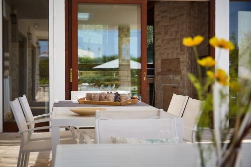 a dining table with white chairs and a table with yellow flowers at Villa D'Aprile Exclusive Luxury Villa with pool, Jacuzzi, SPA in Castellana Grotte