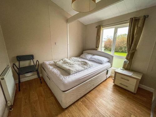 a bedroom with a bed and a chair and a window at Beautiful 6 Berth Lodge With Disabled Access At Cherry Tree Ref 70829c in Great Yarmouth