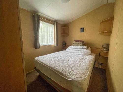 a small bed in a small room with a window at Lovely 8 Berth Caravan At California Cliffs Holiday Park In Norfolk Ref 50053c in Great Yarmouth