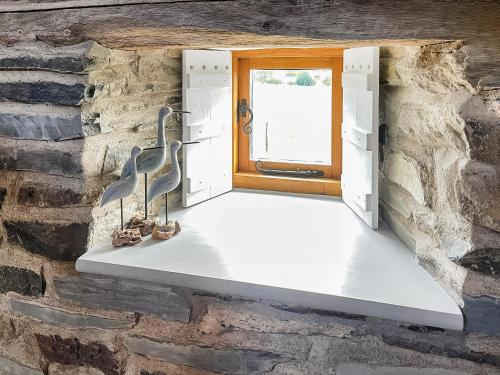 a window in a stone wall with a stair case at Meadow Barn in Shelve