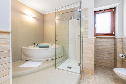 a bathroom with a tub and a glass shower at Villa D'Aprile Exclusive Luxury Villa with pool, Jacuzzi, SPA in Castellana Grotte