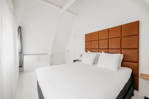 a bedroom with a large bed with a wooden headboard at YAYS Amsterdam Salthouse Canal by Numa in Amsterdam