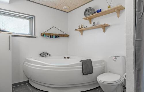 BjerregårdにあるCozy Home In Hvide Sande With Wifiのバスルーム(白いバスタブ、トイレ付)