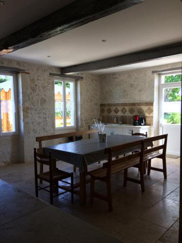 une salle à manger avec une table, des chaises et des fenêtres dans l'établissement Gîte de Couet, à Caumont