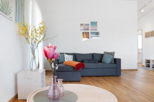 a living room with a couch and a table with flowers at Ferienwohnungen Walz in Pfullendorf