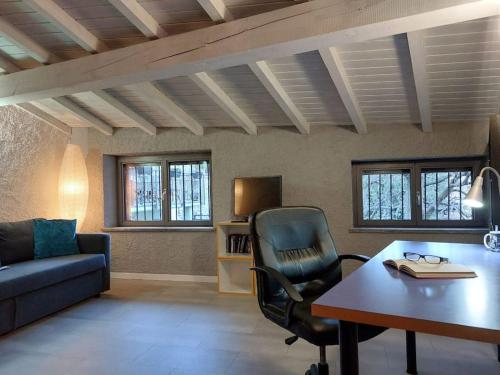 sala de estar con sofá, escritorio y silla en Casa Pedrarias, en Lavena Ponte Tresa