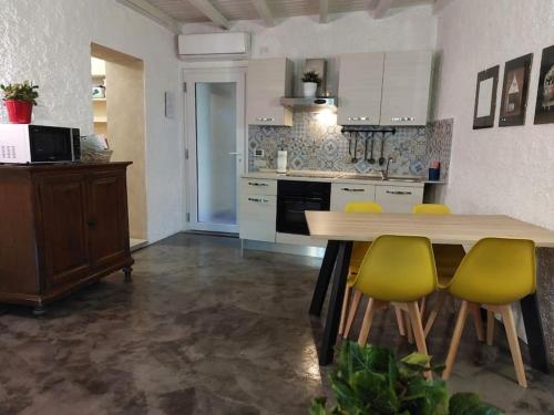 a kitchen with a wooden table and yellow chairs at Casa Pedrarias in Lavena Ponte Tresa