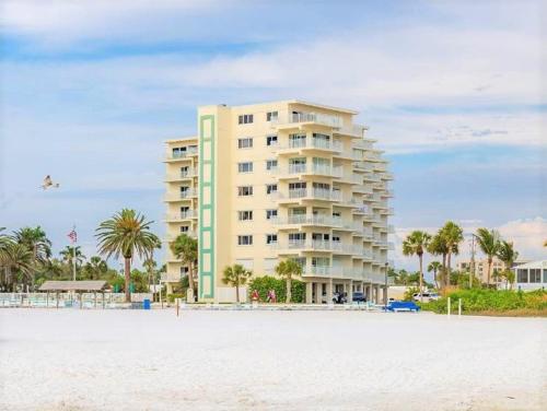 a large building on the beach with palm trees at Jamaica Royale Beachfront Tower in Siesta Key