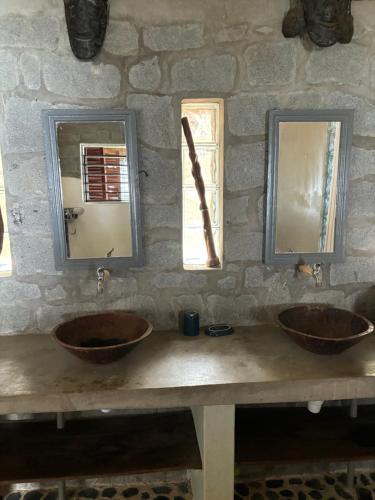 La salle de bains en pierre est pourvue de 2 lavabos et de 2 miroirs. dans l'établissement Nosy Komba Lodge, à Nosy Komba