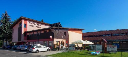 a building with cars parked in a parking lot at Penzión Squash in Liptovský Mikuláš