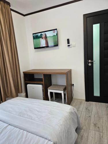 a bedroom with a bed and a tv on the wall at Pensiunea Minerva in Bistriţa