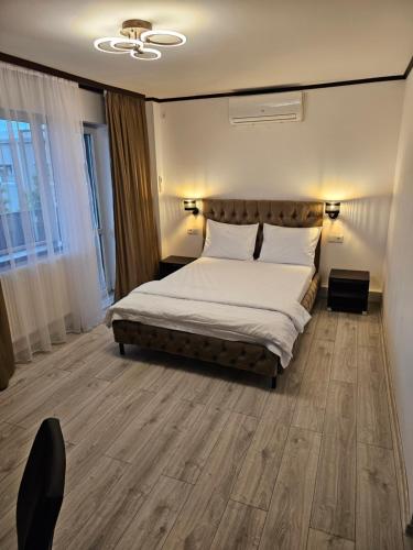 1 dormitorio con 1 cama con sábanas blancas y suelo de madera en Pensiunea Minerva en Bistriţa