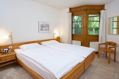 ein Schlafzimmer mit einem großen Bett und einem Stuhl in der Unterkunft Apartment Schweizerhof 402 für zwei-Lenzerheide in Lenzerheide