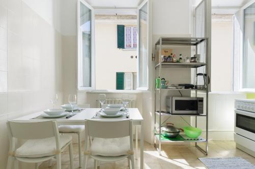 a white kitchen with a white table and chairs at Casa Dolce Casa - Centro Storico in Como