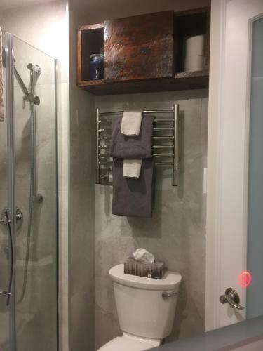 a bathroom with a toilet and a shower with towels at Au Pied de la Montagne CITQ29570Quatre in Mont-Tremblant