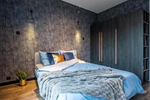 a bedroom with a bed with a blue comforter at Apartament Augustynika in Dąbrowa Górnicza