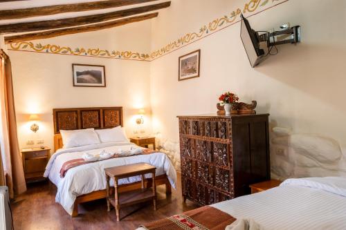 a bedroom with two beds and a chair in it at Hospedaje La Florida in Urubamba