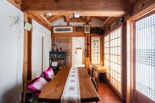 a long wooden table in a room with windows at NamHyunDang - Hanok Korean Traditional House in Seoul