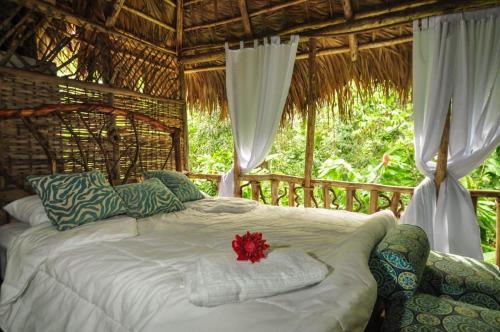 Un dormitorio con una cama con una flor roja. en Tropical Samana, en Santa Bárbara de Samaná