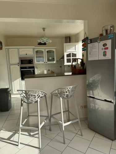 a kitchen with two bar stools and a refrigerator at VILLA C'MARGOT in Marigot