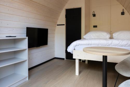 Habitación con 2 camas, mesa y TV. en Boslodges Veluwe en Nunspeet