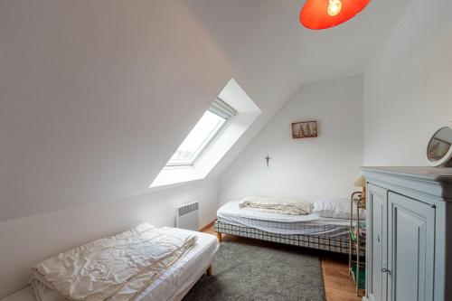 a attic bedroom with two beds and a window at La maison aux volets bleus in Arzon