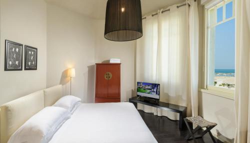 a bedroom with a bed and a television and a window at Hotel Carducci 76 in Cattolica