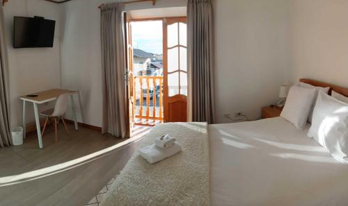 a bedroom with a white bed and a balcony at Hotel Aural in Cajamarca