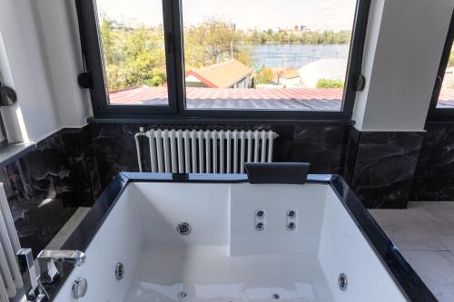 a bath tub in a bathroom with a large window at Villa Sunshine in Sremska Kamenica
