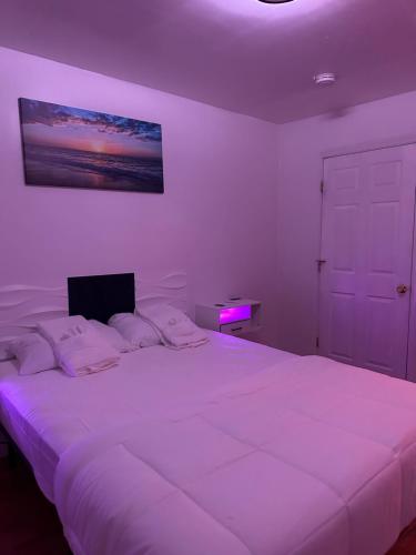 1 dormitorio con 1 cama blanca grande con luz morada en Pipo’s perfect place en Jersey City