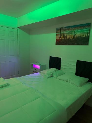 a bedroom with a large white bed with green lights at Pipo’s perfect place in Jersey City