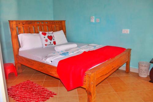 Un dormitorio con una cama de madera con una manta roja. en Shanzu Budget Traveler Homestay, en Mombasa