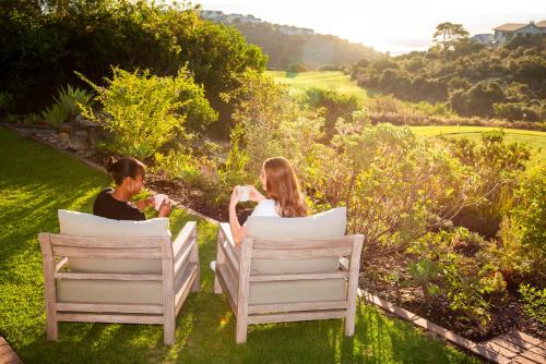 two people sitting in chairs on the grass at Pezula Magic Retreat - 4 Bedroom Home with Inverter in Knysna