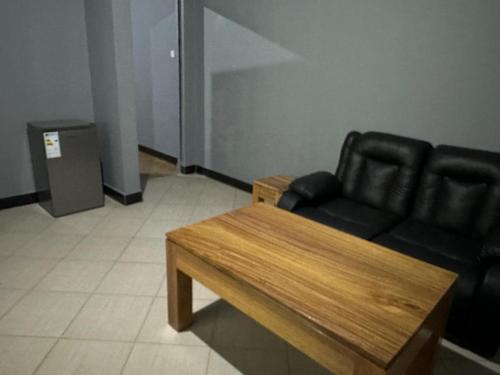 a living room with a black couch and a wooden table at Maro Homestay Sango in Old Moshi