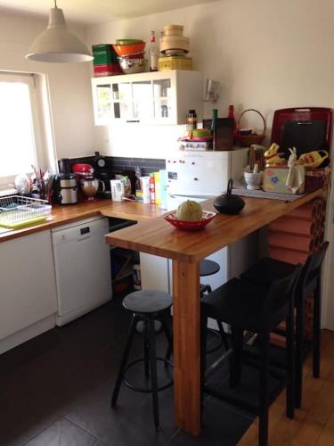 - une cuisine avec une table en bois et quelques tabourets dans l'établissement Joli 3 pièces + terrasse LaVillette, à Paris