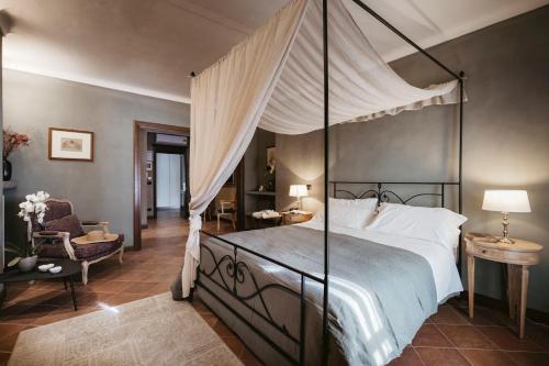a bedroom with a canopy bed and a chair at Agriturismo Tenuta La Romana in Nizza Monferrato