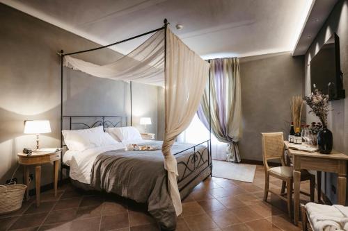 a bedroom with a canopy bed and a desk at Agriturismo Tenuta La Romana in Nizza Monferrato