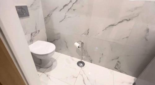 a white bathroom with a toilet and marble walls at Great holiday home for vacations & holidays in Tetney