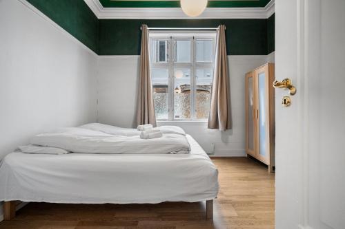 a bedroom with a bed with a window and white sheets at Experience the luxury lifestyle 100m from Bryggen! in Bergen