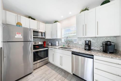 a kitchen with white cabinets and stainless steel appliances at Sun and Sea By Beachside Management in Siesta Key