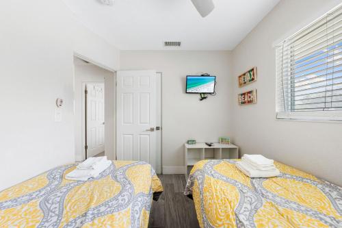 a bedroom with two beds and a tv on the wall at Sun and Sea By Beachside Management in Siesta Key