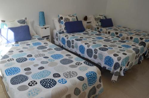 two beds with blue and white covers in a room at Vv Puesta de Sol in Alojera