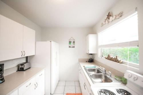 a white kitchen with a sink and a window at Living the Dream in Siesta Key