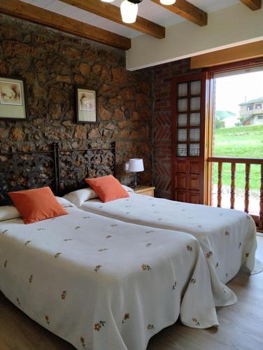 two beds in a bedroom with a stone wall at Hospedaje Vega in Santillana del Mar