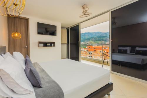 um quarto com uma grande cama branca e uma grande janela em Hotel Perlatto em Bello