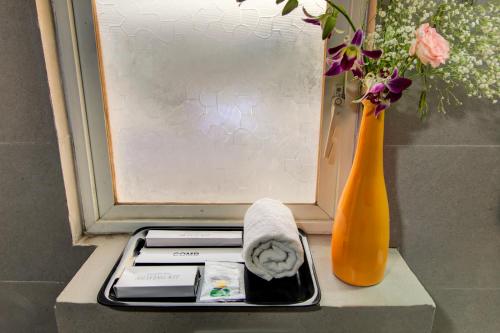 een dienblad met een handdoek en een vaas met bloemen bij Housemate Hotel in Pune
