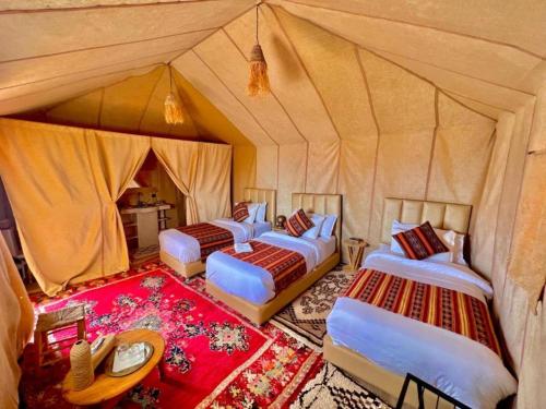 a group of four beds in a tent at Sahara Crown Luxury Camp in Merzouga
