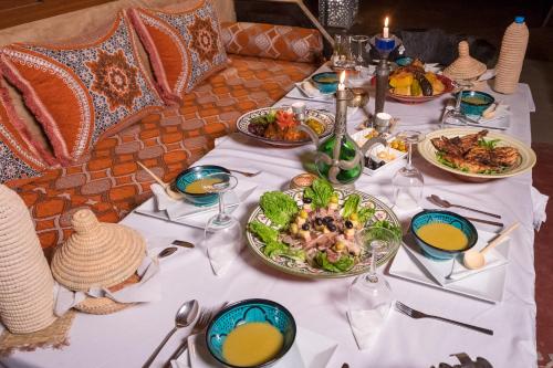 a white table with plates of food on it at Sahara Luxury Camp & Camel Trek in Merzouga