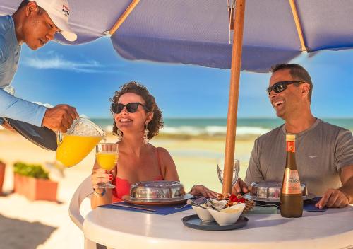 a group of people sitting at a table on the beach at Hotel Praia do Sol in Ilhéus