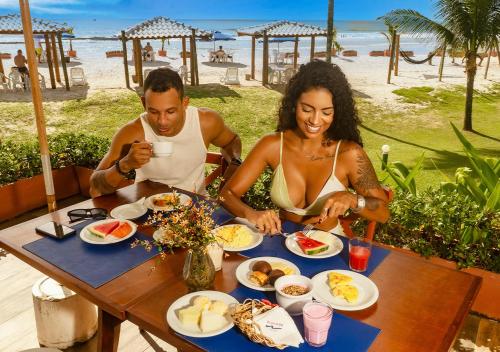 Um homem e uma mulher sentados à mesa com comida. em Hotel Praia do Sol em Ilhéus